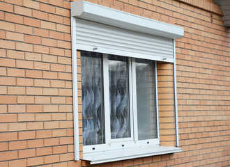 Brick house window with rolling shutter for home protection.