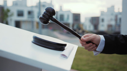 Property auction on real estate. Close-up auctioneer banging with mallet gavel by tribune outdoors. Auction bid sale jughment. - obrazy, fototapety, plakaty