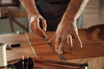 Man working with piece of leather in workshop, closeup