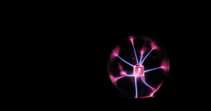 Tesla coil experiment with electricity, glowing plasma lamp. Tesla plasma ball with electrode and pink and blue lightnings in dark isolated on black background. Electricity or plasma crackling.
