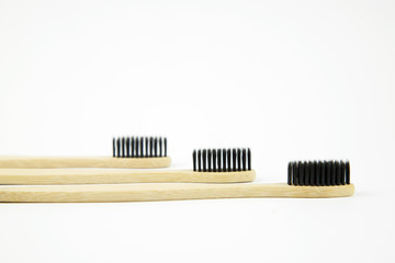 Three bamboo eco toothbrushes with natural bristles lie on a white background. Refusal of plastic....