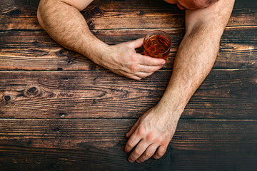 Drunk man with a glass of alcohol lies on a wooden table. The concept of alcoholism and alcohol dependence.