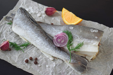 Fresh sea fish with herbs, spices and lemon on a black background.