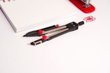 concept worktable design, compass, white notebook, stapler, two click on white background