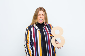 young pretty blonde woman angry, anger, disagreement, holding a number 8.