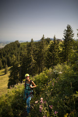 Pretty, female climber on a via ferrata -  climbing on a rock in Swiss Alps - Approach phase