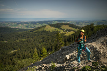 Fototapeta na wymiar Pretty, female climber on a via ferrata - climbing on a rock in Swiss Alps - Approach phase