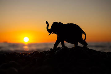 Fototapeta na wymiar Silhouette of an elephant figurine on the background of the sea and the sunset sky. Balnce, Harmony & Meditation