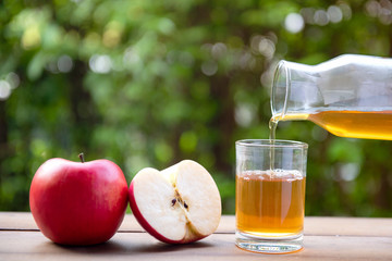 Apple juice pouring from red apples fruits on wood Floor and Bokeh Background