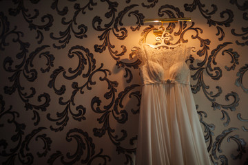 Bride fashion dress hanging on a wall being lit by a lamp