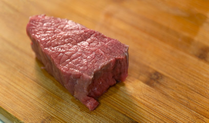 A piece of meat prepared for cutting. Lies on a wooden board.