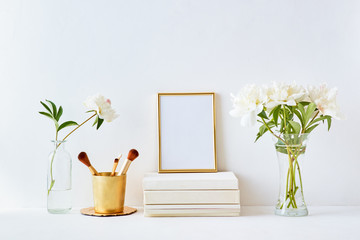 Home interior with decor elements. Gold frame, white peonies in a vase, cosmetic set