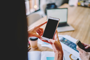 Faceless colleagues browsing cellphones in workplace