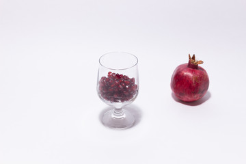 Glass of fresh red pomegranate seeds on white background