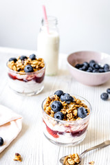 Morning granola with yogurt and berries on white kitchen background