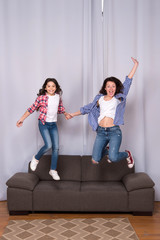 happy sisters jump in freedom sense. mother and daughter having fun on weekend. move in new house....