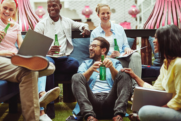 Diverse businesspeople drinking beers after work in an office lo