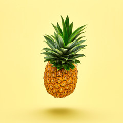 Flying in air pineapple tropical fruit on yellow. Healthy vitamin pineapple, vegan dieting food. Organic whole sweet fresh fruits. Levitation, falling fly pineapple creative concept