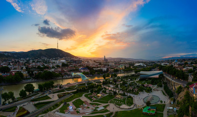 The evening panorama of the old town in the old district of Avlabari, Holy Trinity Cathedral and Rike Park, the Kura river reflects the evening city lights in Tbilisi, Georgia. © miklyxa