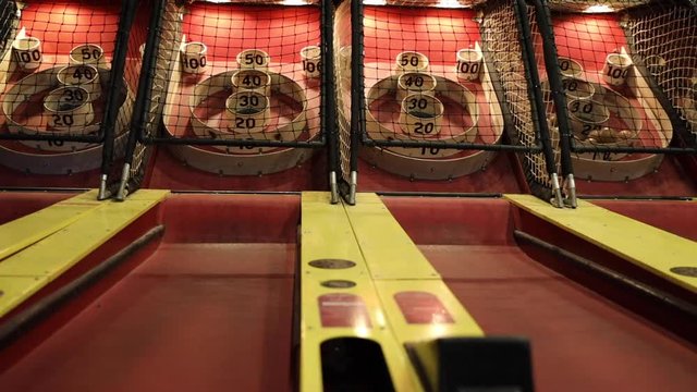 Two people at an arcade playing skee ball together. Only hands seen occasionally. Shot in between