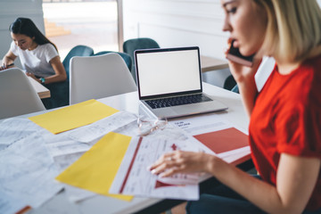 Blurred businesswoman reading papers and speaking on smartphone during work