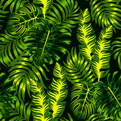 Summer seamless tropical pattern with bright green and yellow plants and leaves on a dark background.  Beautiful exotic plants.  Seamless pattern with colorful leaves and plants.