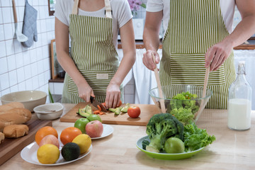Happy caucasian couple family cooking in modern kitchen at home with love. Married romantic man and woman  cooking fresh vegetable salad.Healthy lifestyle concept.
