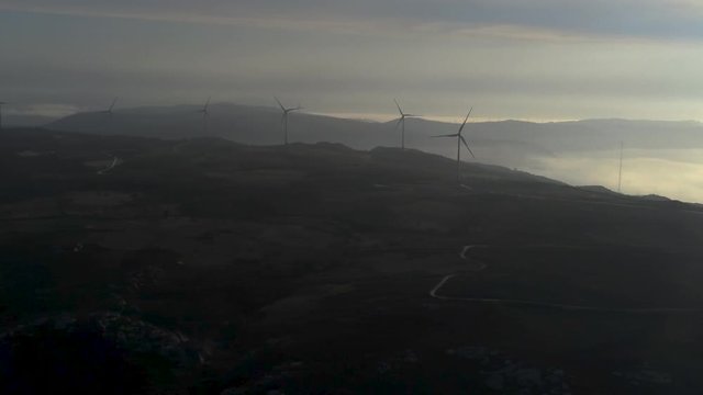 Aerial view of silhouette wind turbines at sunset with ocean on background near playa Barizo, La Coruna, Galicia Spain. Drone footage pan from left to right