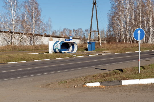 Bus stop for intercity transport with a rural toilet on the highway near the village of Shila on a sunny day in autumn.