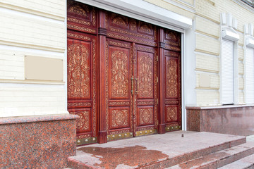 brown wooden entrance doors with a traditional hand-carved pattern with granite threshold and stone...