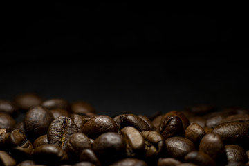 Fototapeta premium Coffee in beans on dark background. Abstract background texture.Coffee beans texture. Food background of coffee beans