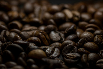 Dark background and texture of coffee beans, selective focus, closeup grains.