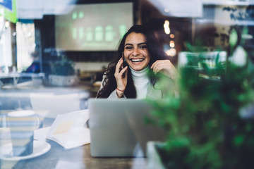 Smiling lady speaking on cellphone in cafe