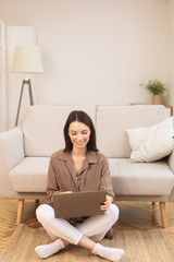 Girl working on laptop sitting on the floor