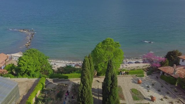 Flying above beautiful garden to the coastline where the waves crash on the shore