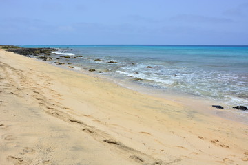 Fototapeta na wymiar A sandy beach and blue, turquoise ocean, sea with rock on the shore