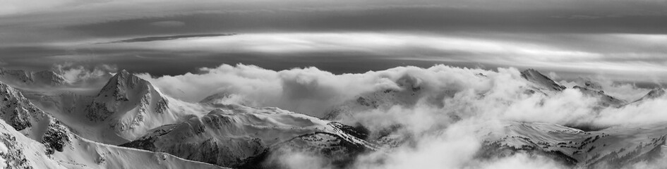 Whistler, British Columbia, Canada. Beautiful Panoramic View of the Canadian Snow Covered Mountain Landscape during a cloudy and vibrant winter sunset. Black and White