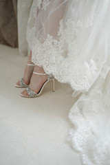 Legs of the bride, white shoes with shining crystals of rhinestones, dress of the bride. Accessories for a wedding day.