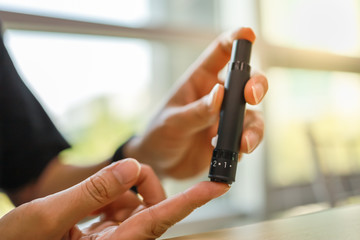 Naklejka premium Close up of man hands using lancet on finger to check blood sugar level by Glucose meter. Use as Medicine, diabetes, glycemia, health care and people concept.