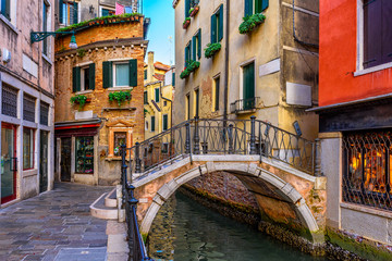 Narrow canal with boat and bridge in Venice, Italy. Architecture and landmark of Venice. Cozy cityscape of Venice.