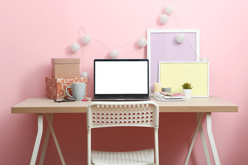 Workplace near the wall with a modern laptop. The modern workplace of a student, designer, creative person.