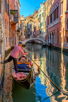 Narrow canal with gondola and bridge in Venice, Italy. Architecture and landmark of Venice. Cozy cityscape of Venice.