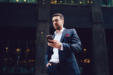 Fototapeta premium Bewildered businessman with smartphone in city