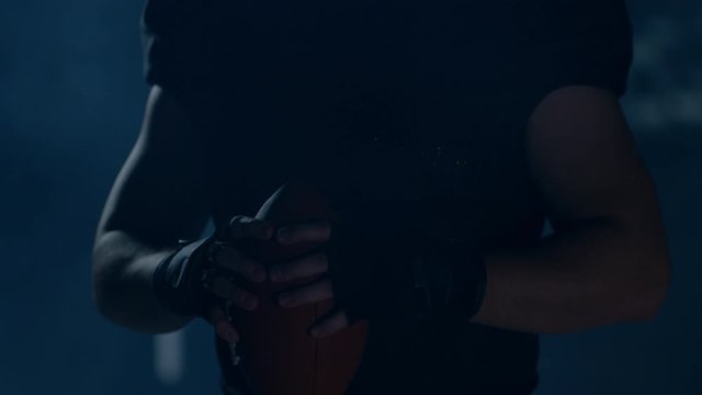 CU Portrait of American football player in protective uniform posing against bright flashing lights. Shot on ARRI Alexa Mini 60 FPS slow motion