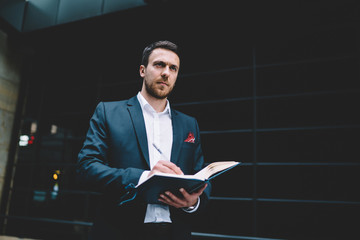 Pensive male office employee in formal wear with day planner at city street