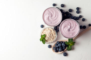 two fresh blueberry yogurt with blueberries on a white texture table, top view