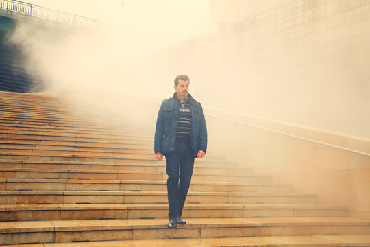 Adult Man Coming Down The Stairs And Out Of The Fog. Survival Concept