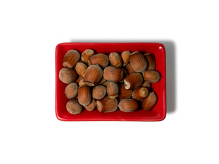Hazelnuts in a red rectangular saucer isolated on white background. View from above