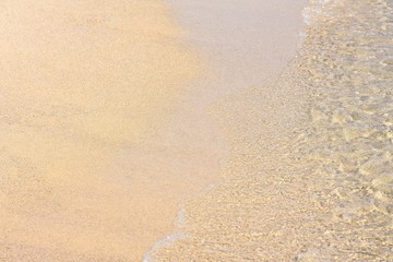 Transparent sea waves with white foam and clean yellow sand. Summer background.  Sea coast with a beautiful soft wave. blue sea wave with white foam on a clean sandy shore, selective focus. 