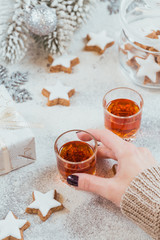 Fototapeta na wymiar Woman holds a glass of whiskey, brandy or liquor. Cookies, drinks and winter holiday decorations